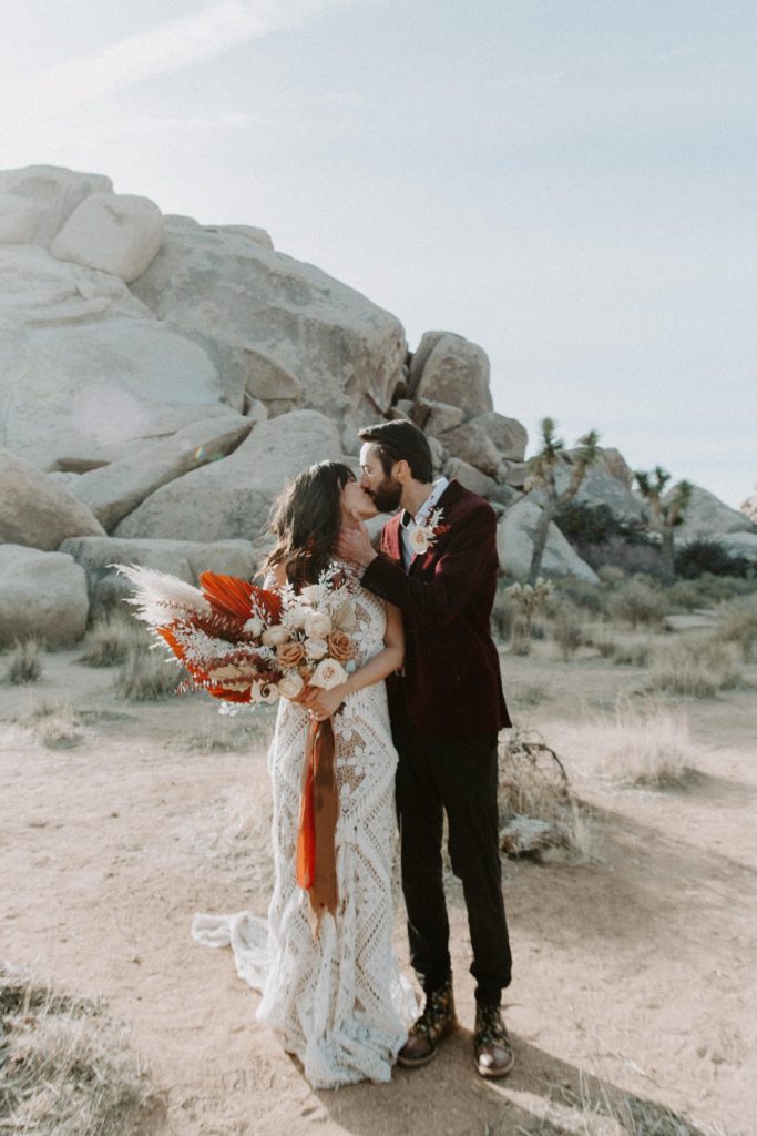 A man bringing his partner in for a kiss during their all day elopement in Joshua Tree National Park