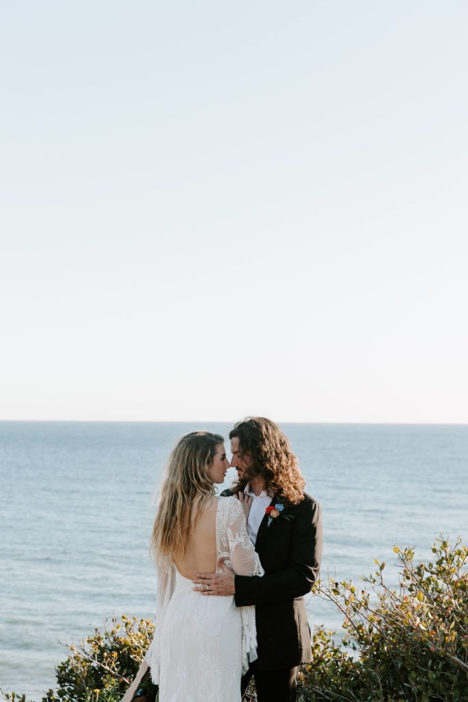A newly wed couple embracing after saying their vows as the sun is setting on the cliffs in Malibu