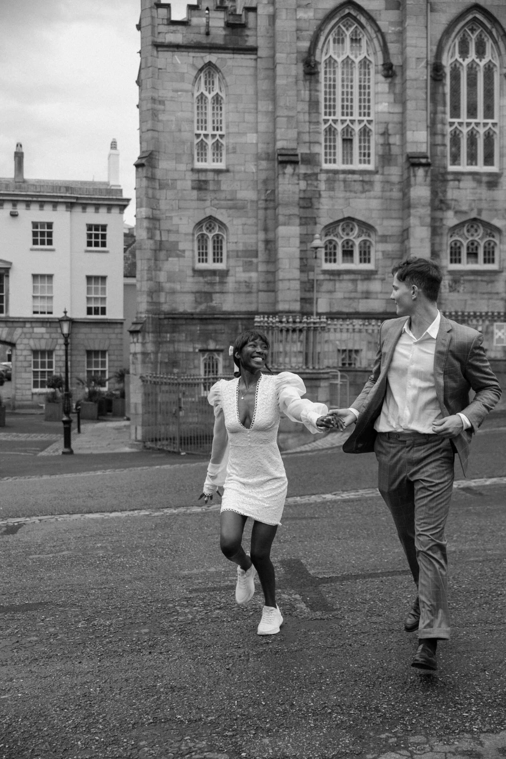 A newlywed couple holding hands and running through the streets of Ireland during their summer elopement in Dublin