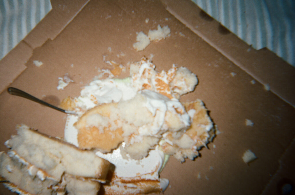 Cake that has been destroyed and is sitting on a pizza box after a light night beach wedding on 30-A