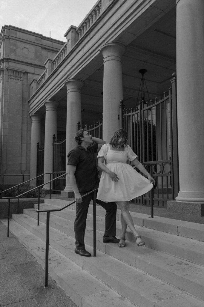 A newly engaged couple standing on the steps of the Nashville symphony building in downtown Nashville as they fix themselves during their engagement photos