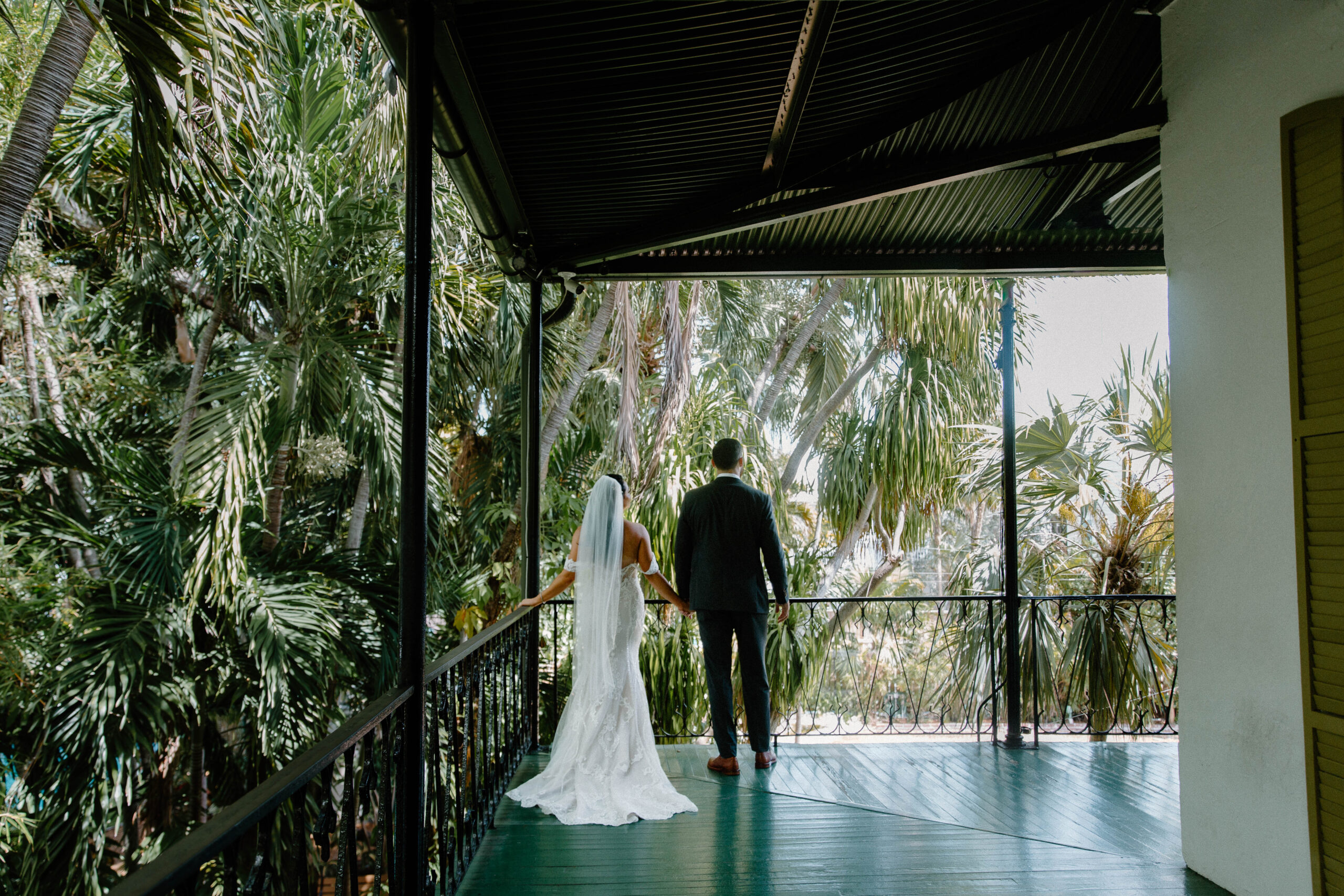 A couple standing at the edge of the second story of the Hemingway house overlooking the gardens during their key west elopement