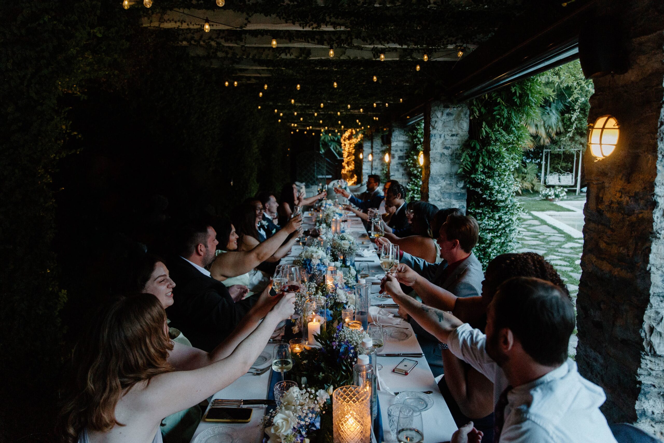 Wedding guests and couple clinking their wine glasses during an intimate wedding dinner on Lake Como