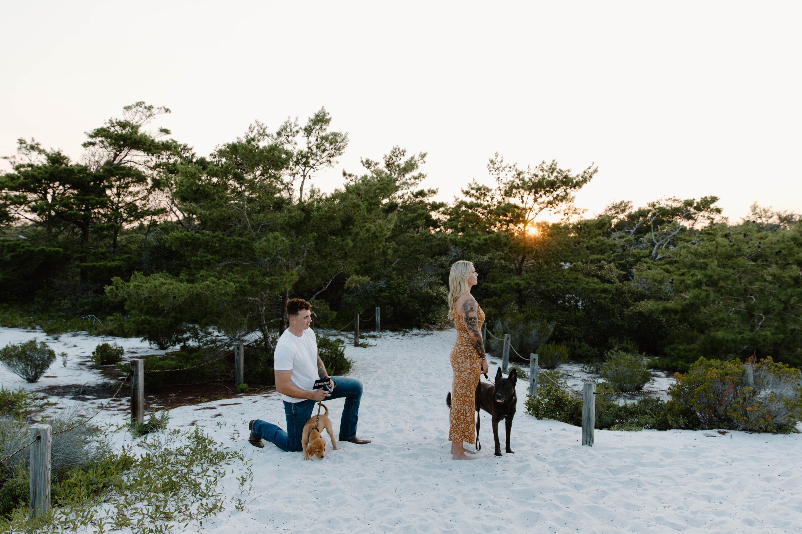 A woman with her back to her partner as he is down on one knee about to propose during a Destin Florida couple photo shoot