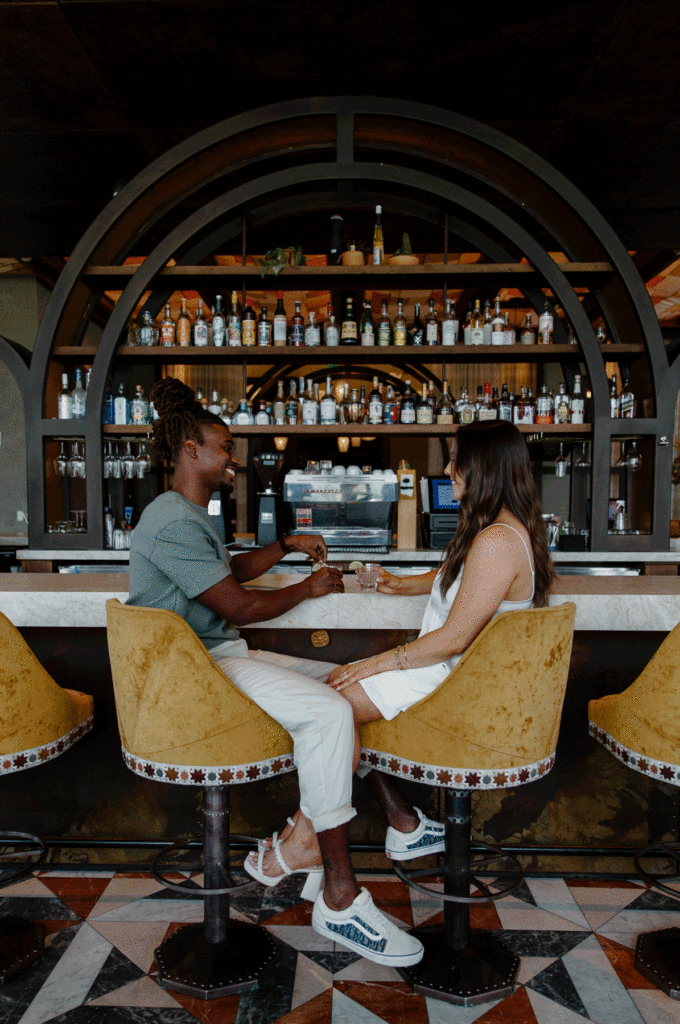 A woman and her partner sitting in a bar as they are about to take tequila shots during their couples photo shoot in Atlanta, Georgia at Three Arches bar