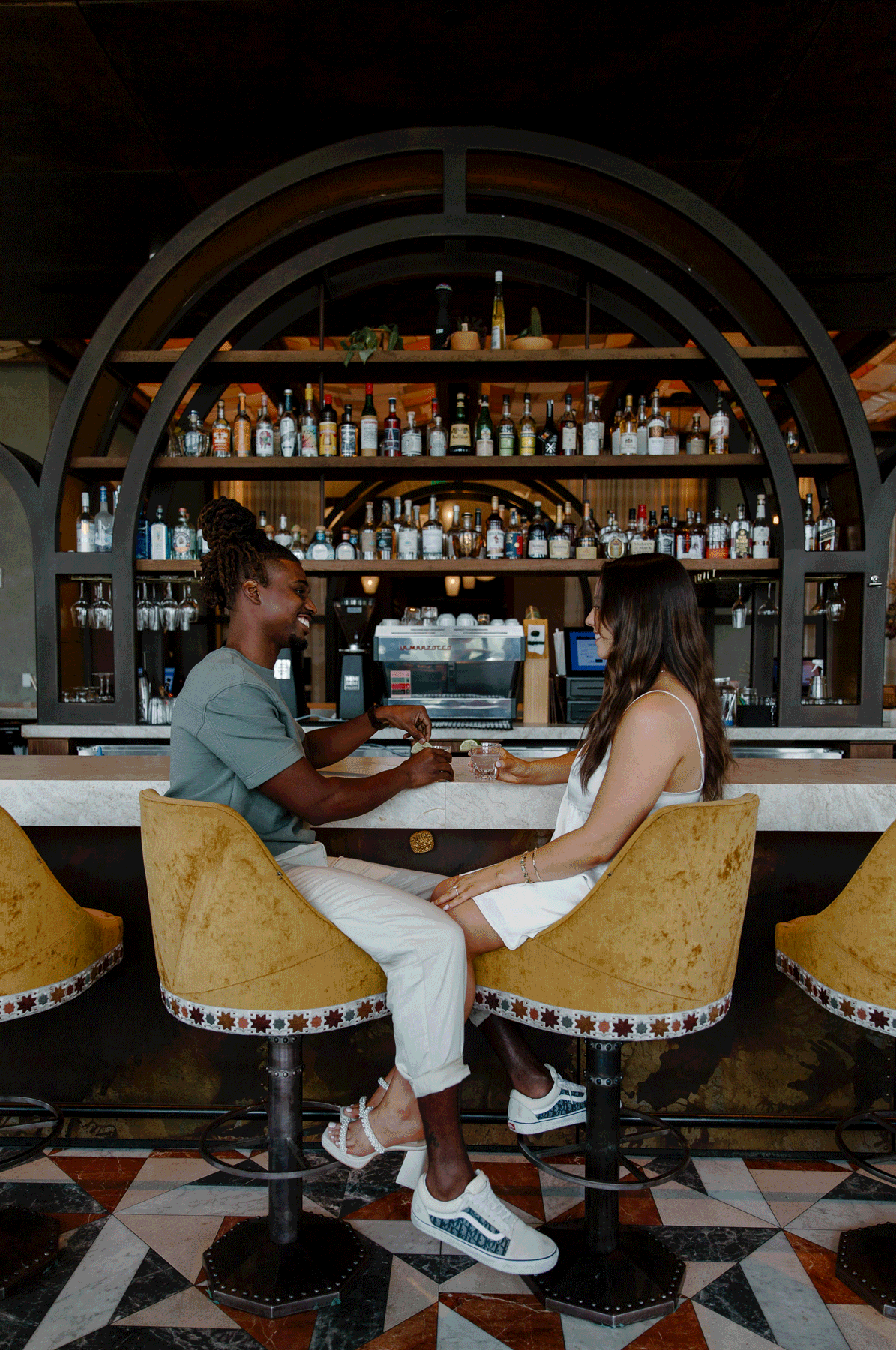 A woman and her partner sitting in a bar as they are about to take tequila shots during their couples photo shoot in Atlanta, Georgia at Three Arches bar