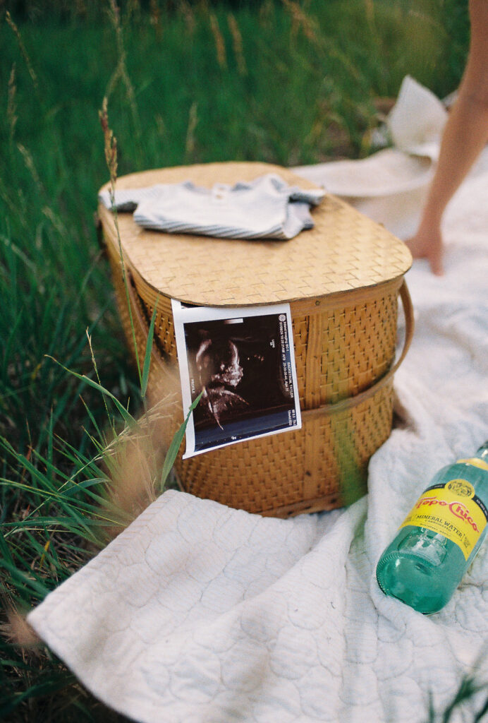 A sonogram hanging out the side of a picnic basket during a maternity session in Albuquerque, New Mexcio