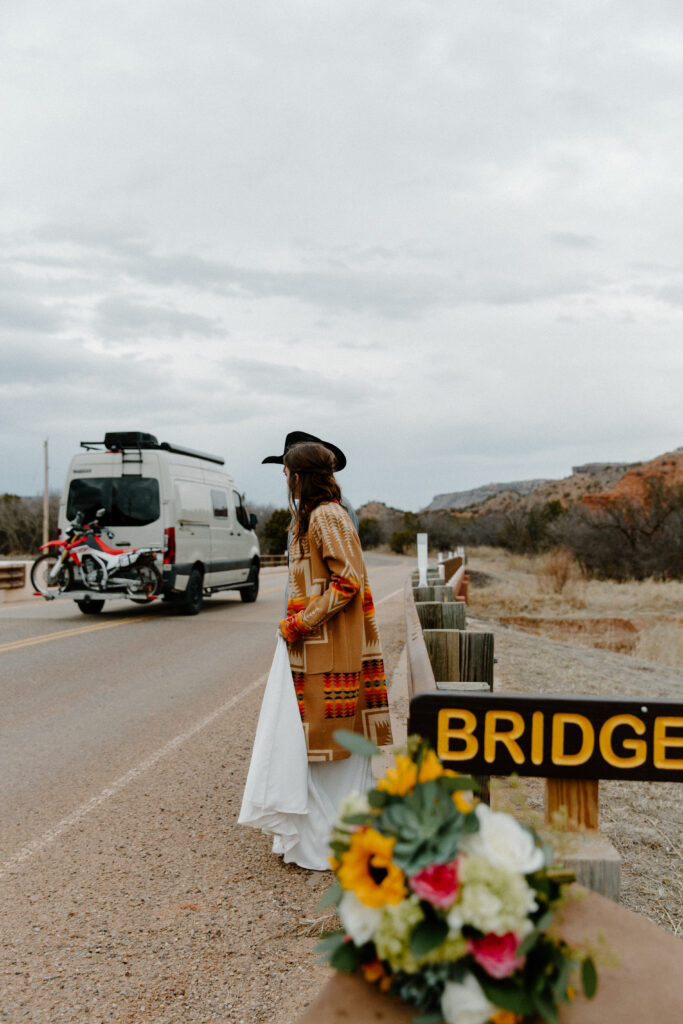 A couple in wedding attire about to cross a street as a camper passes them during exploring on their Texas elopement