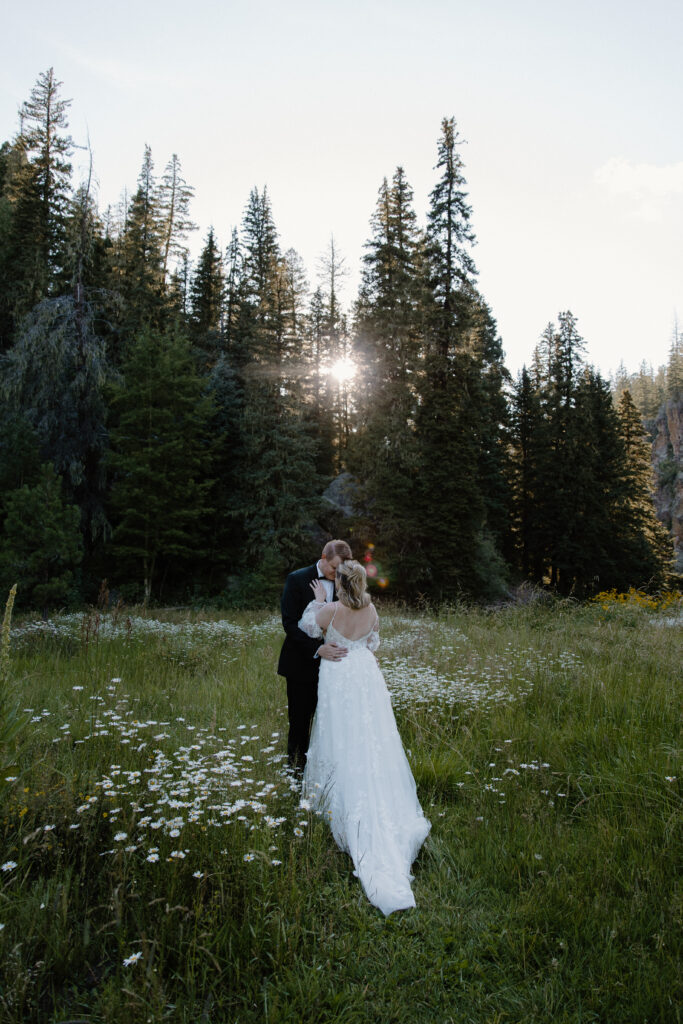 A newly wed couple resting their foreheads together in a field of wildflowers during their Santa Fe National Forest elopement