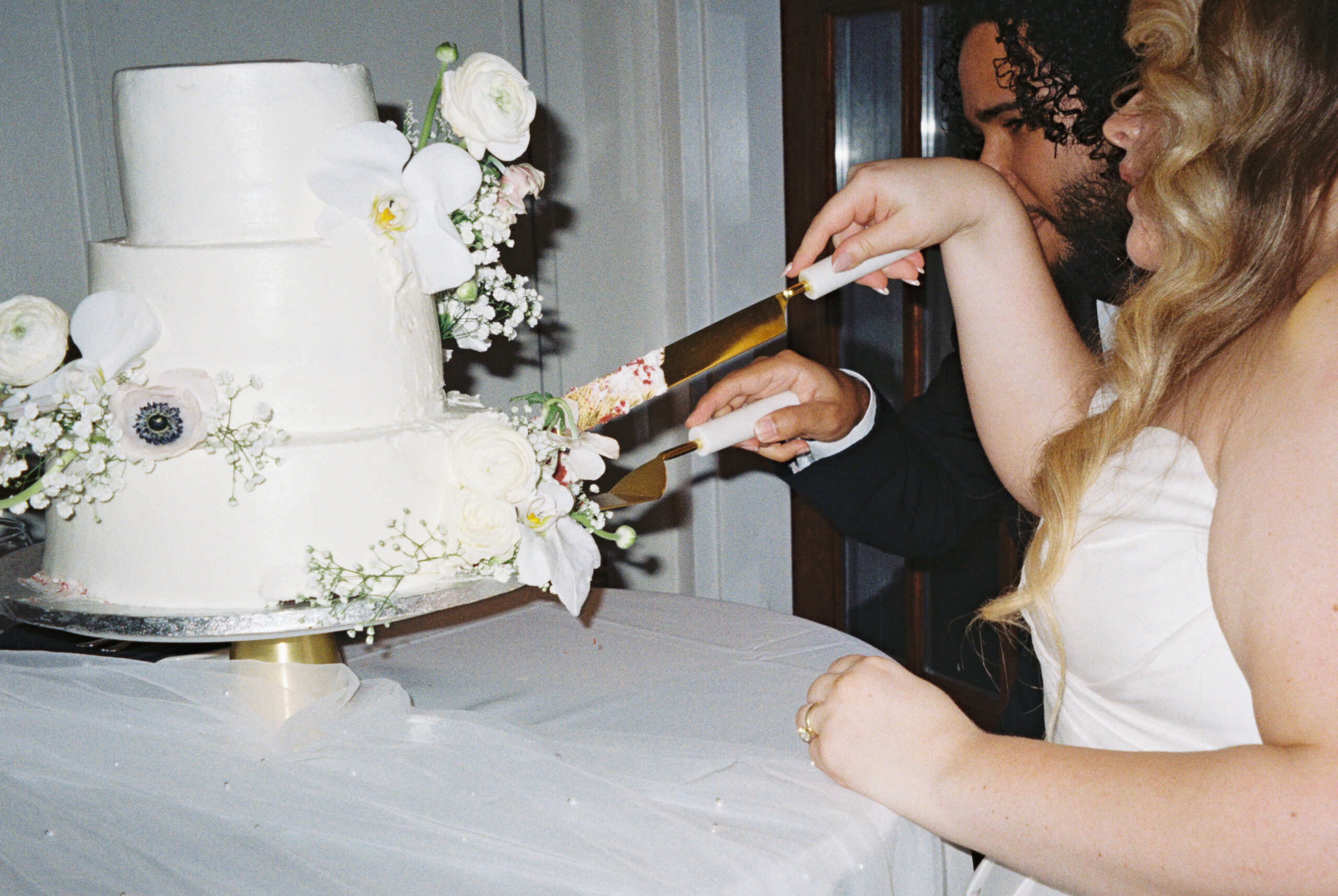 A couple in wedding attire cutting their red velvet cake shot on film during their Florida wedding