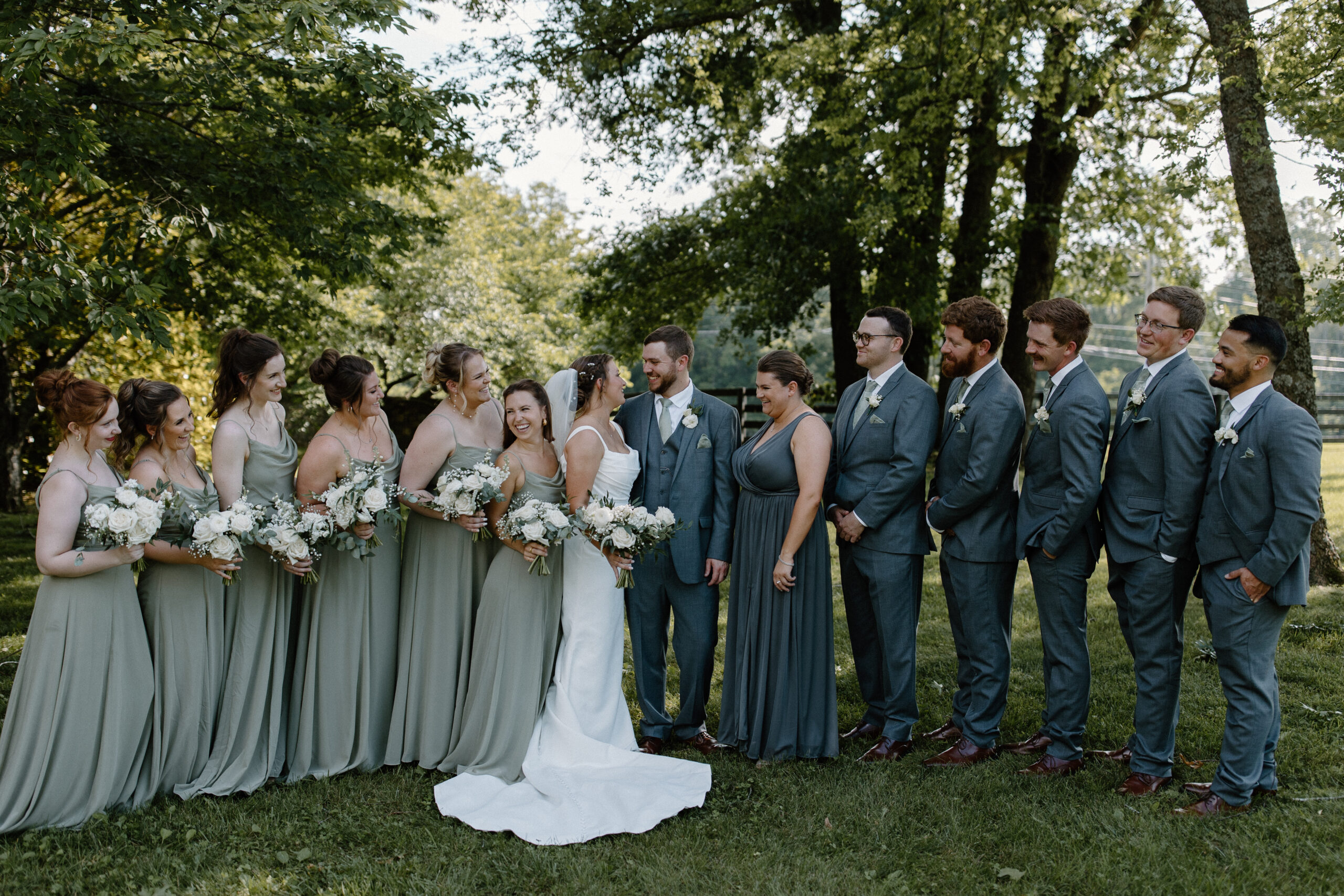 A bride and groom looking at each other as the rest of the wedding party look at them and at each other during an outdoor Tennessee wedding