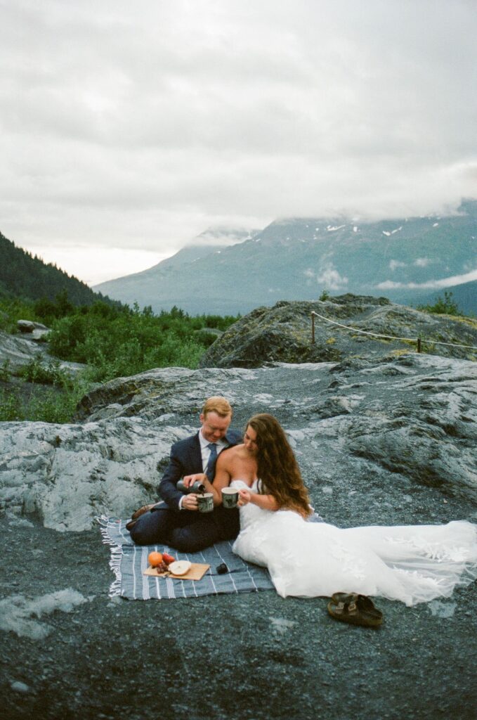 A couple sitting at a high point in Kenai Fjords National Park during their sunrise picnic elopement in Alaska