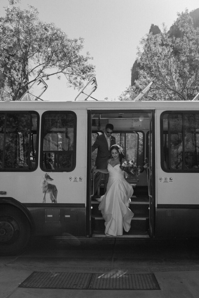 A couple in wedding attire stepping out of Zion National Parks bus system on the way to their elopement during their Utah elopement in the fall