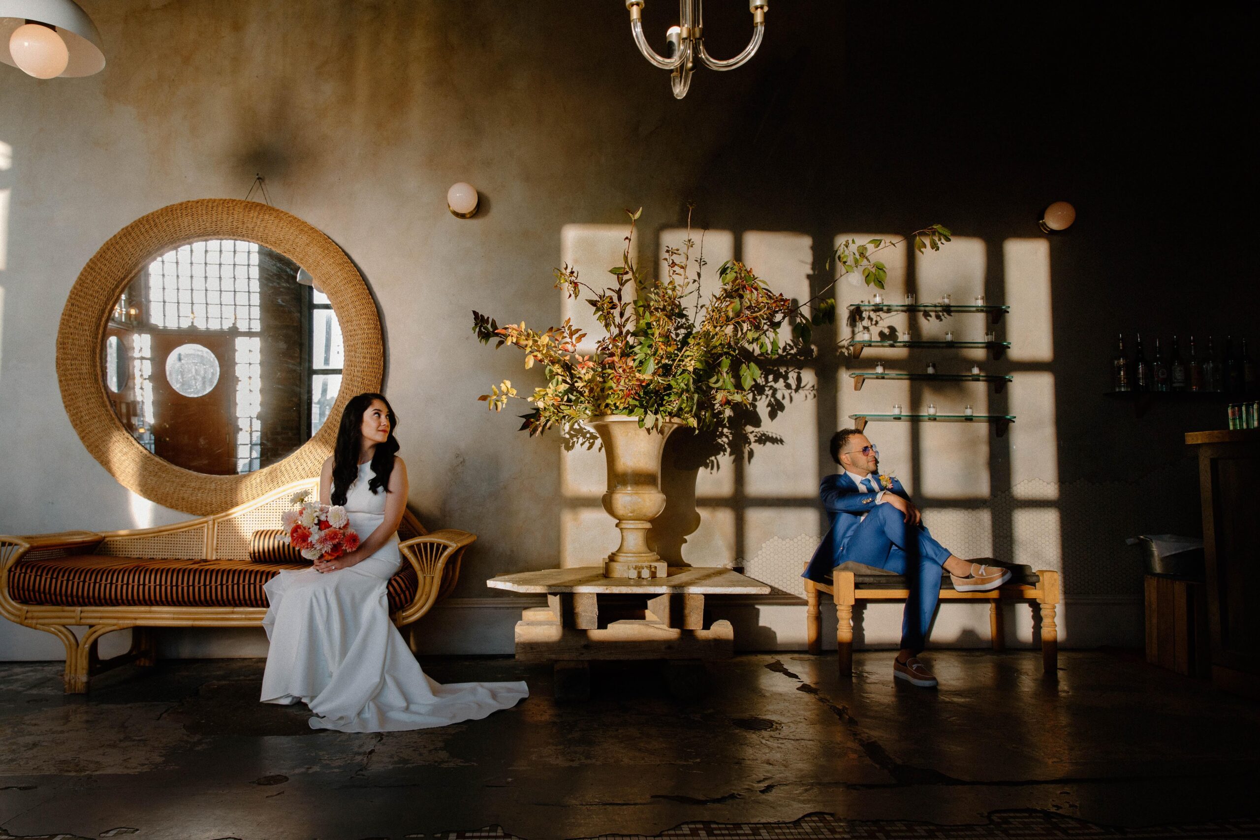 A woman and her partner sitting on opposite sides of a fall as sunlight filters through the windows during their intimate Brooklyn wedding in New York