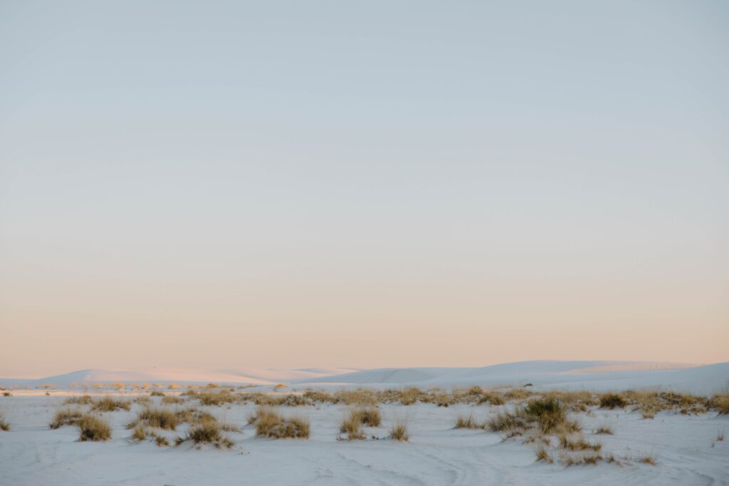 The sun casting the sand dunes in a pink glow during an all day adventure elopement at White Sands National Park