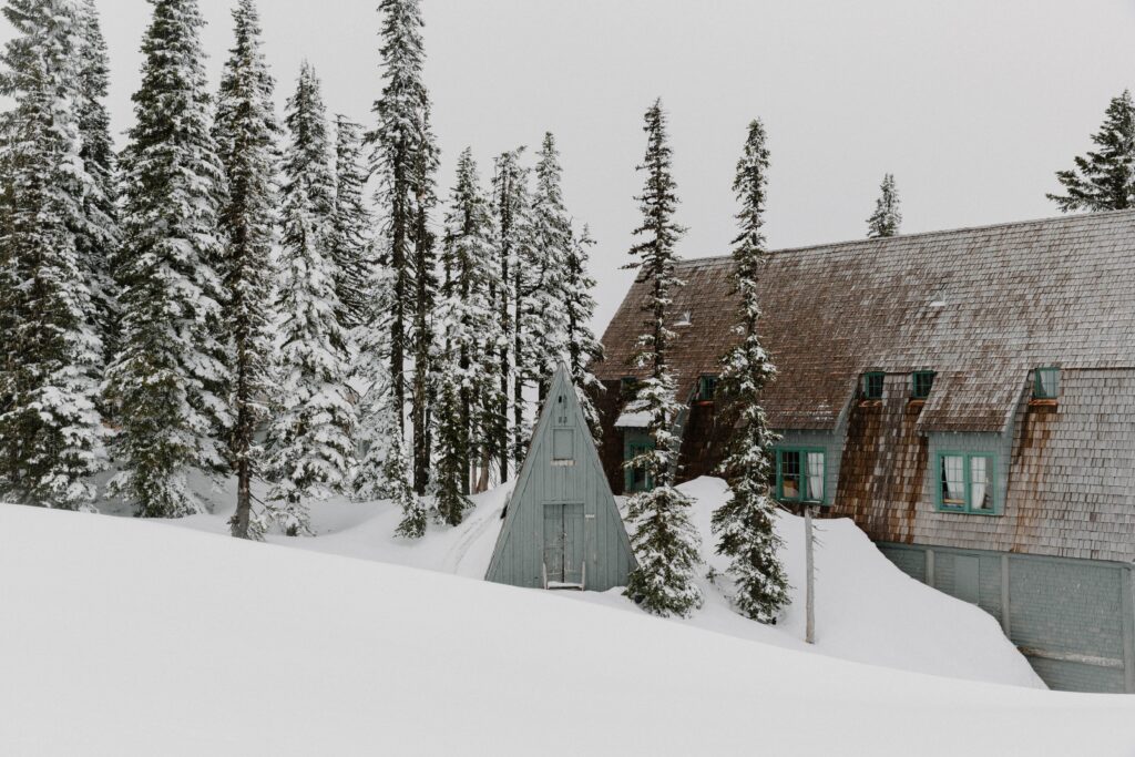 A blue a-frame cabin surrounded by snow and pine trees during a winter elopement in Washington State