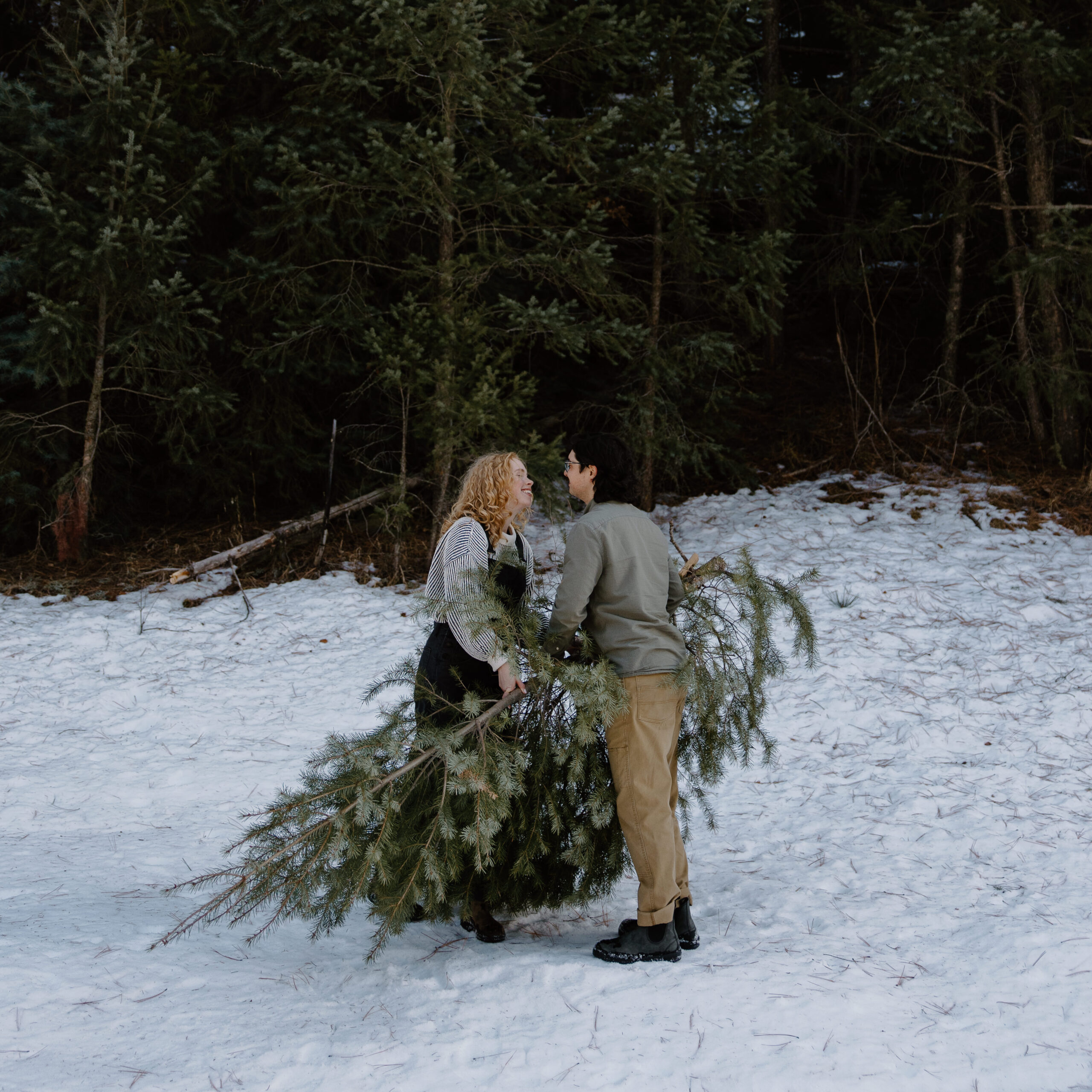 A woman smiling at her partner as he stands on the other side during their winter engagement photos in New Mexico