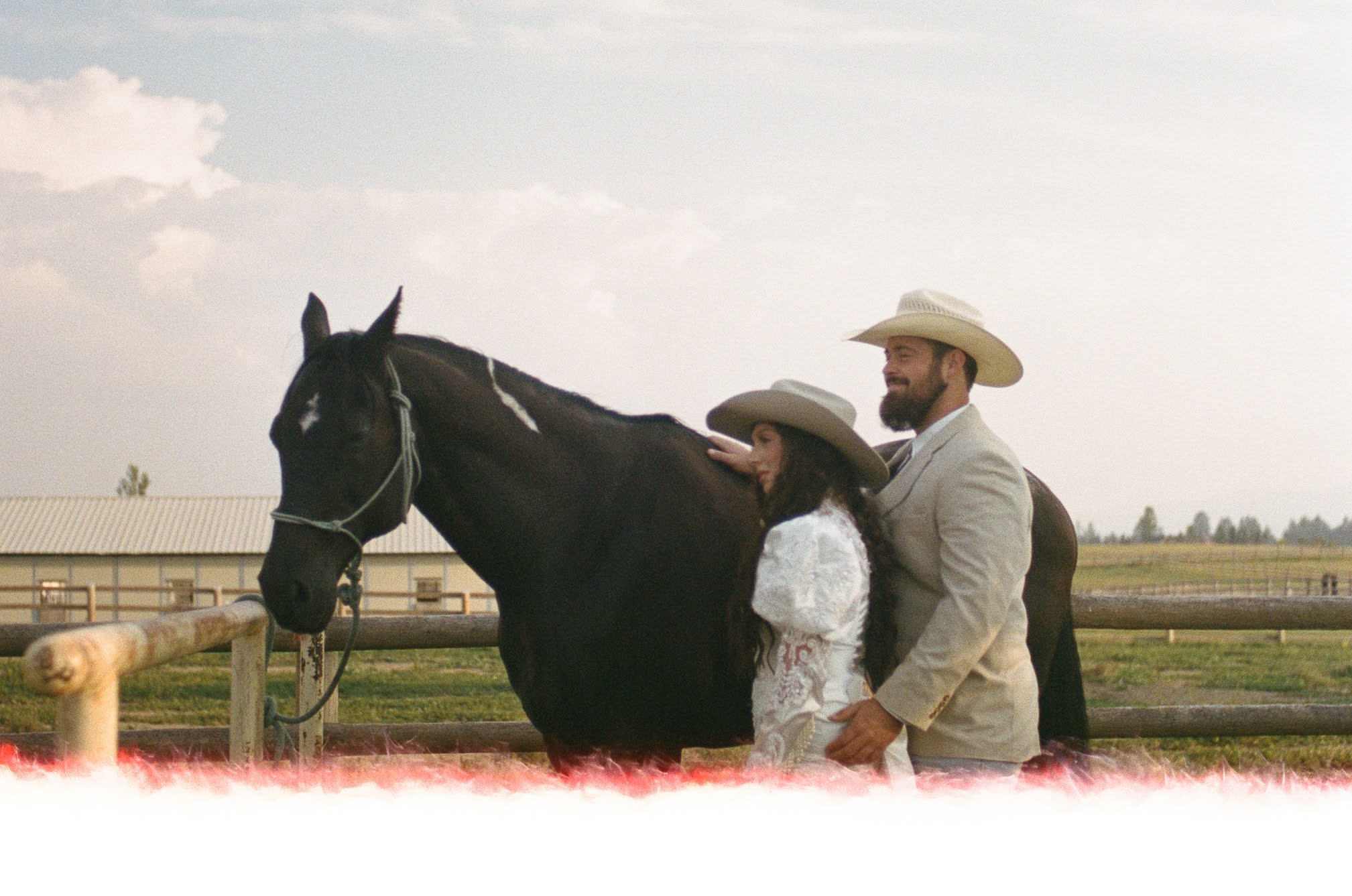 A couple in wedding attire standing next to a horse getting it ready to ride during their all day adventure wedding in Montana
