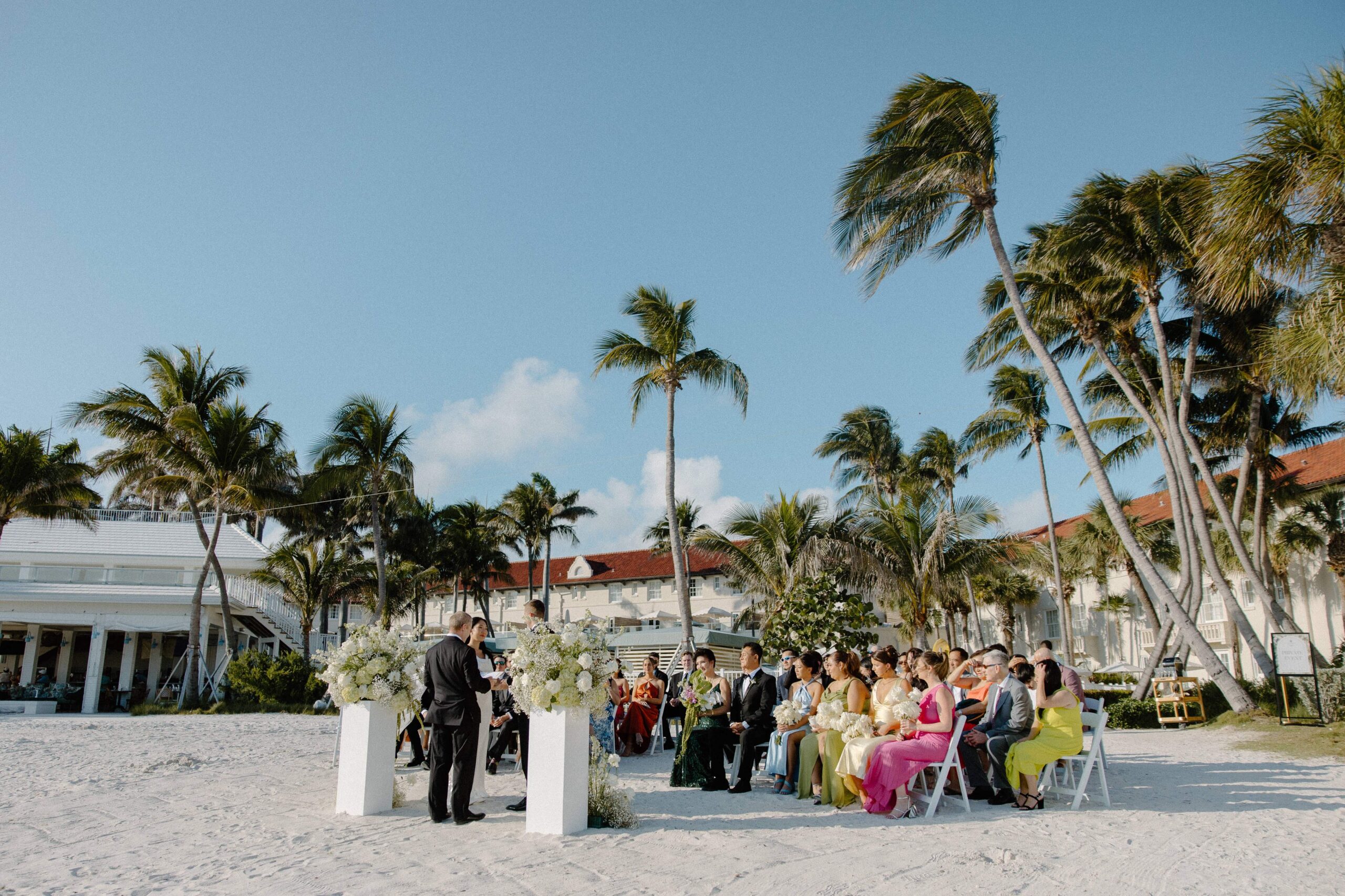 An outdoor wedding ceremony on the beach surrounded by palm tress during a winter wedding in Key West, Florida