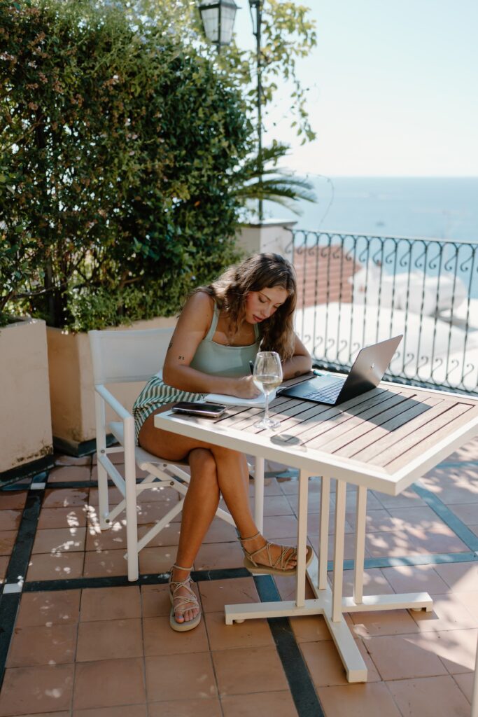 A woman sitting on a terrace writing her vows overlooking Positano, Italy