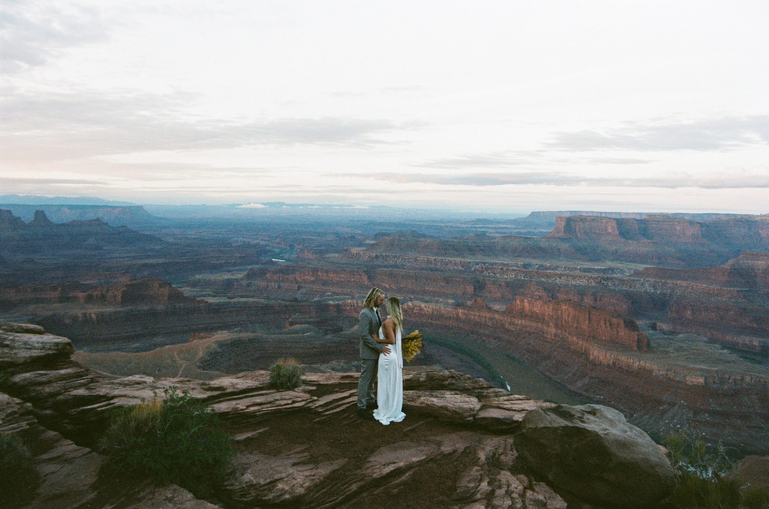A couple standing on the edge overlooking Dead Horse State Park during their Utah elopement