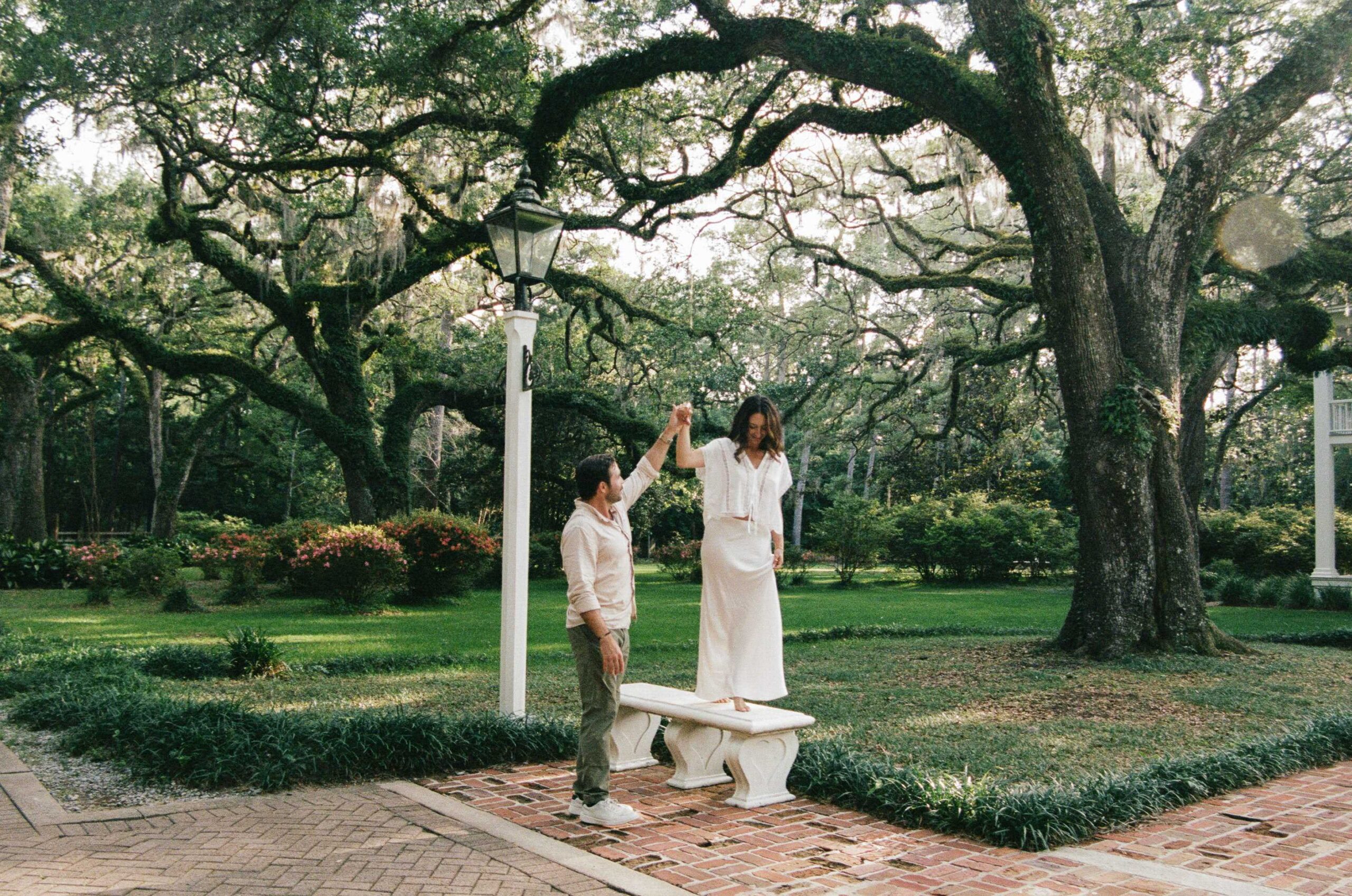 A man helping his partner walk on a bench during a garden photoshoot in Santa Rosa Beach on film