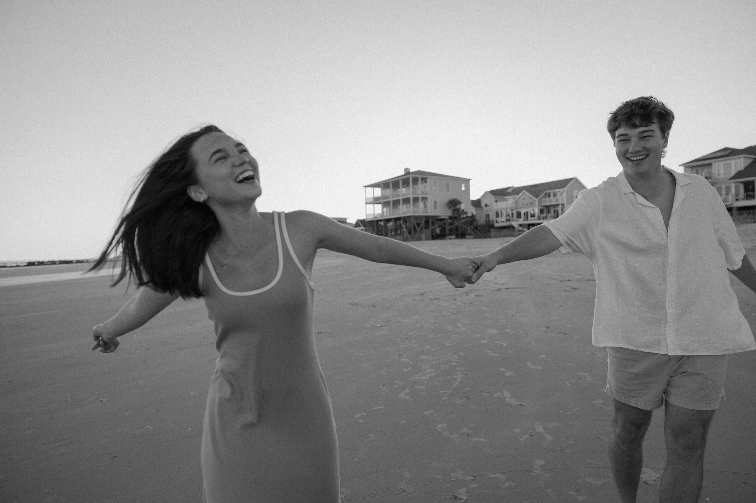 A man swinging his partner as they both laugh along the beach during their spring photoshoot