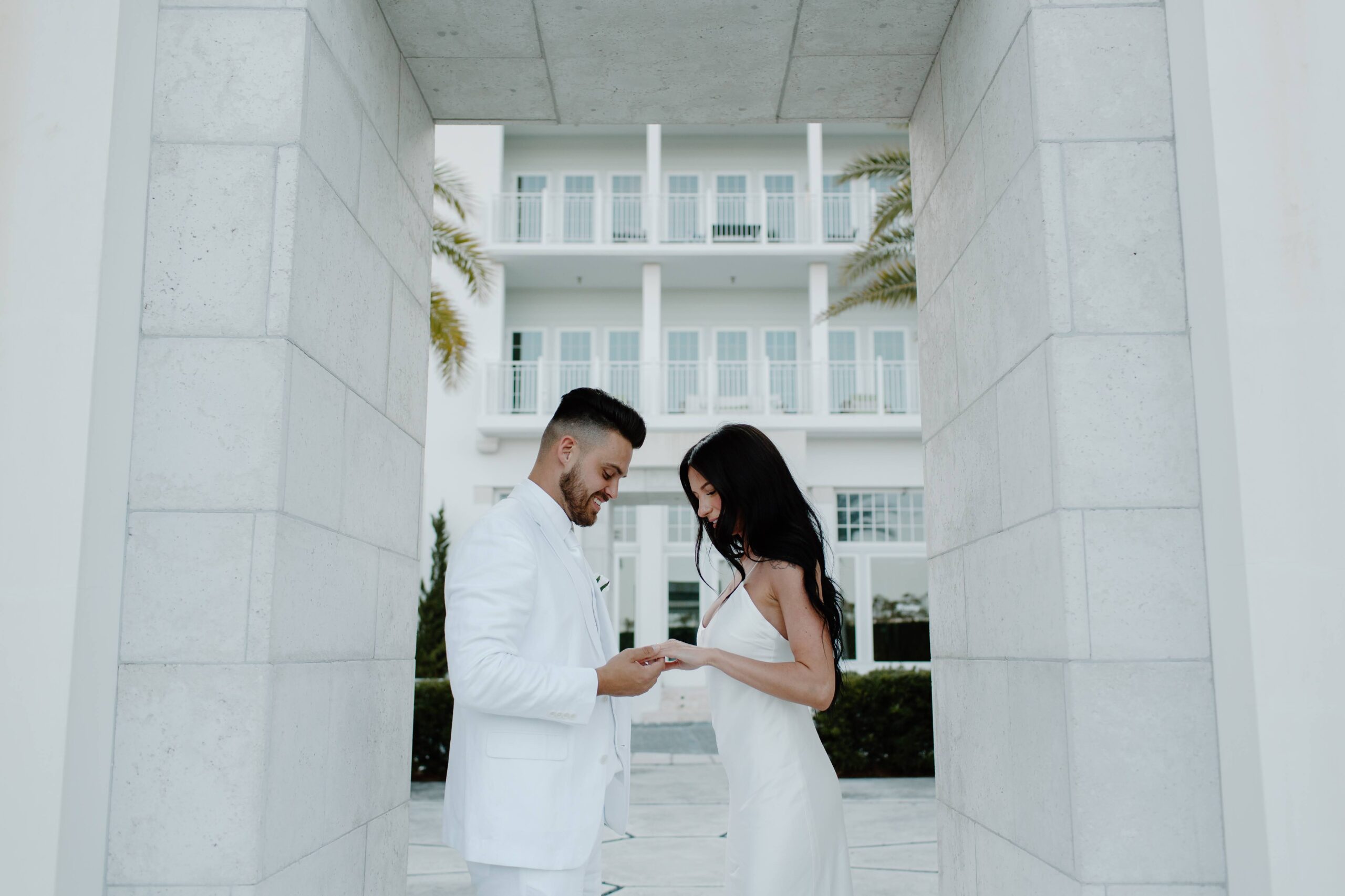 A man putting a wedding band on his partners hand as they finish their wedding ceremony on 30-A