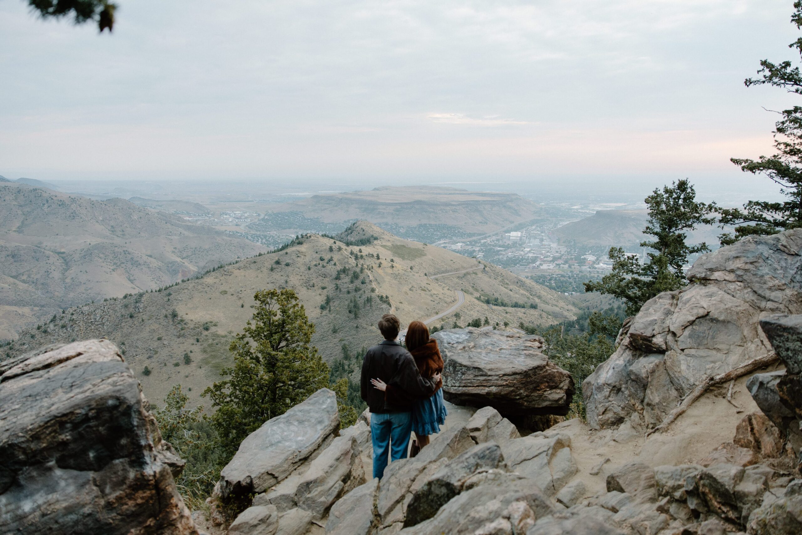 Couple hugging at mountain overlook during sunrise engagement photos.