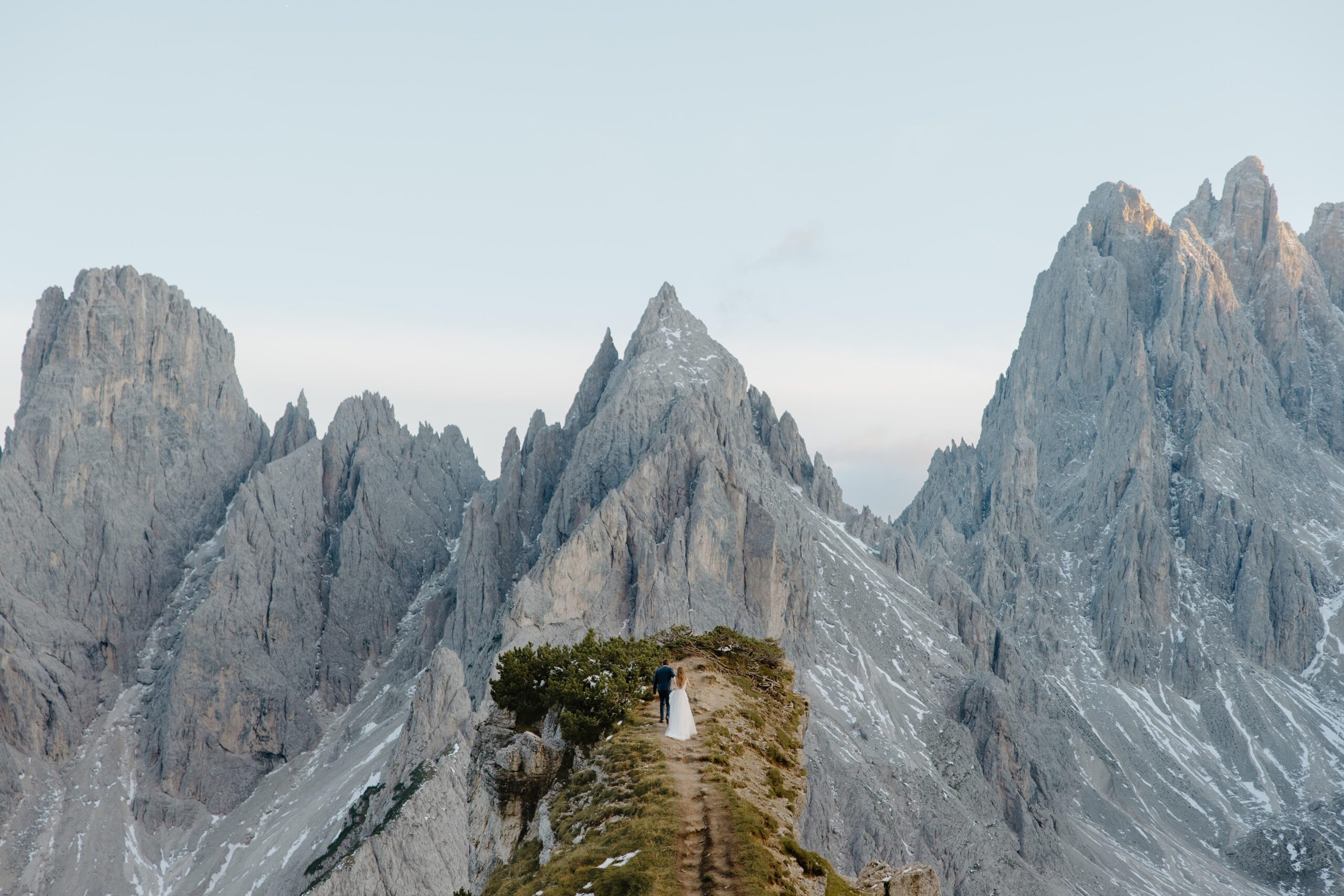 A couple in wedding attire hiking out over the dolomites during their adventure Italy elopement