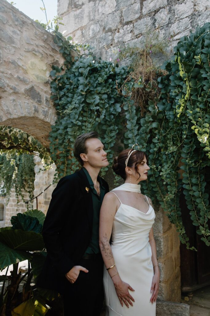 Couple standing in a lush courtyard with ivy in Hvar, Croatia.