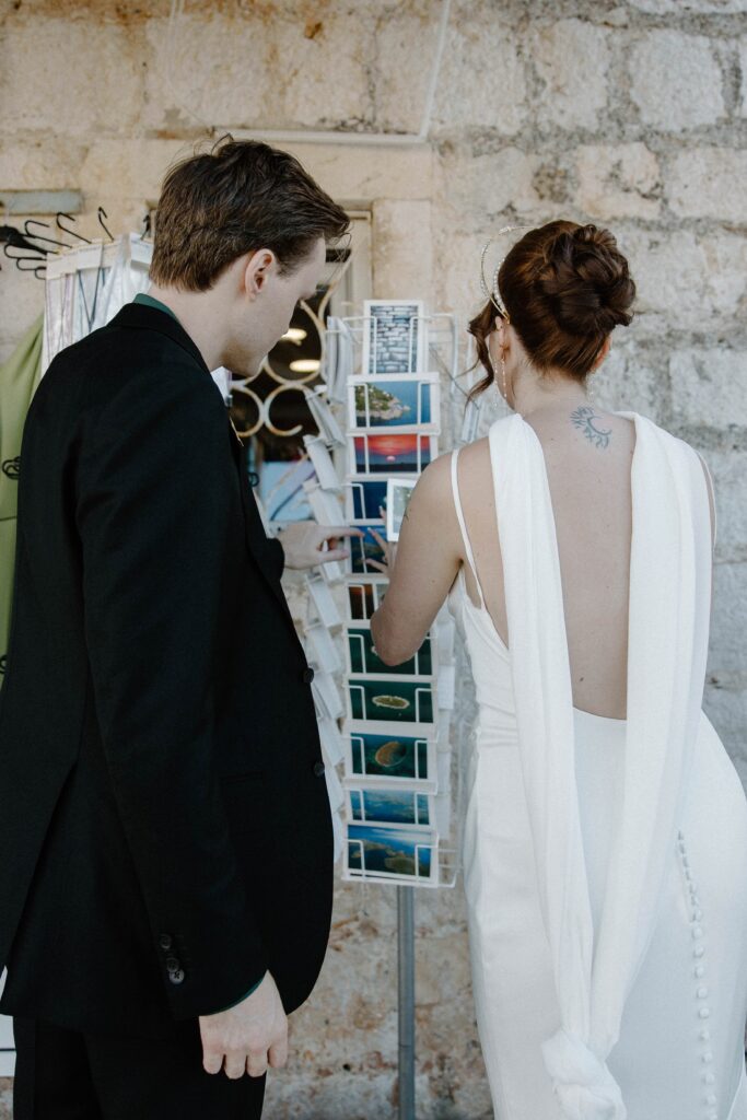 Bride and groom browsing postcards together in Hvar’s charming streets.