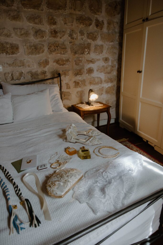 Elopement day details sitting on a bed in a rental during their Hvar, Croatia adventure elopement