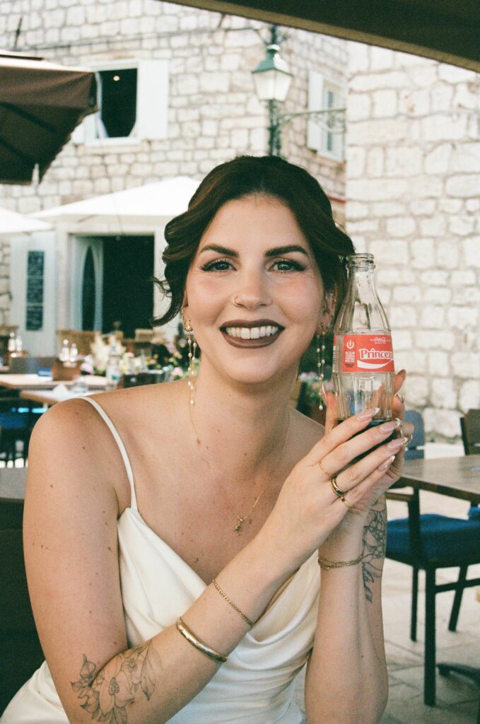 Bride smiling at the camera holding a Coca Cola during Hvar elopement.