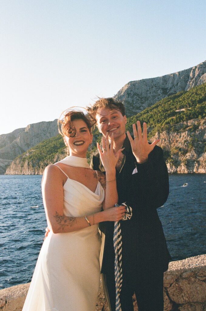 A couple in wedding attire smiling big and showing off their new wedding bands during their island elopement in Croatia