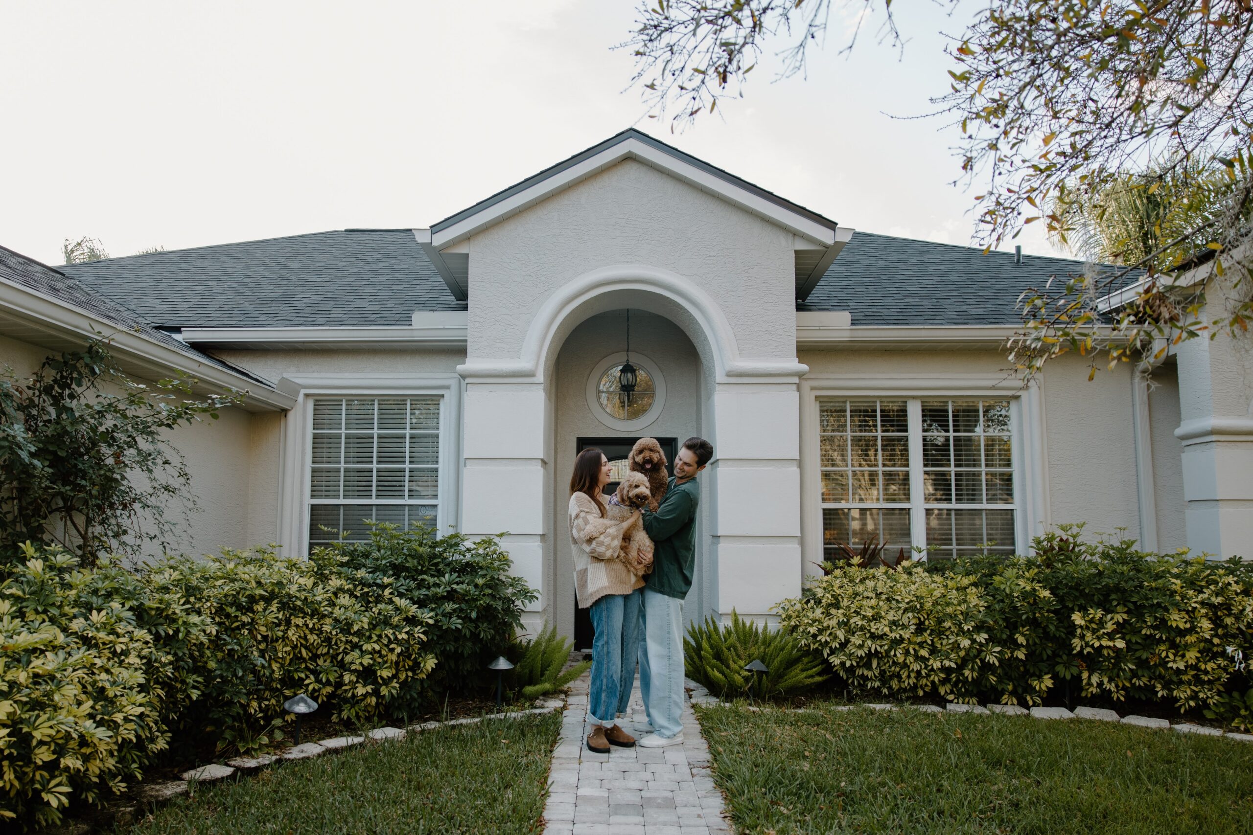 A couple holding their dogs as they stand in front of their house during their Florida couple photos