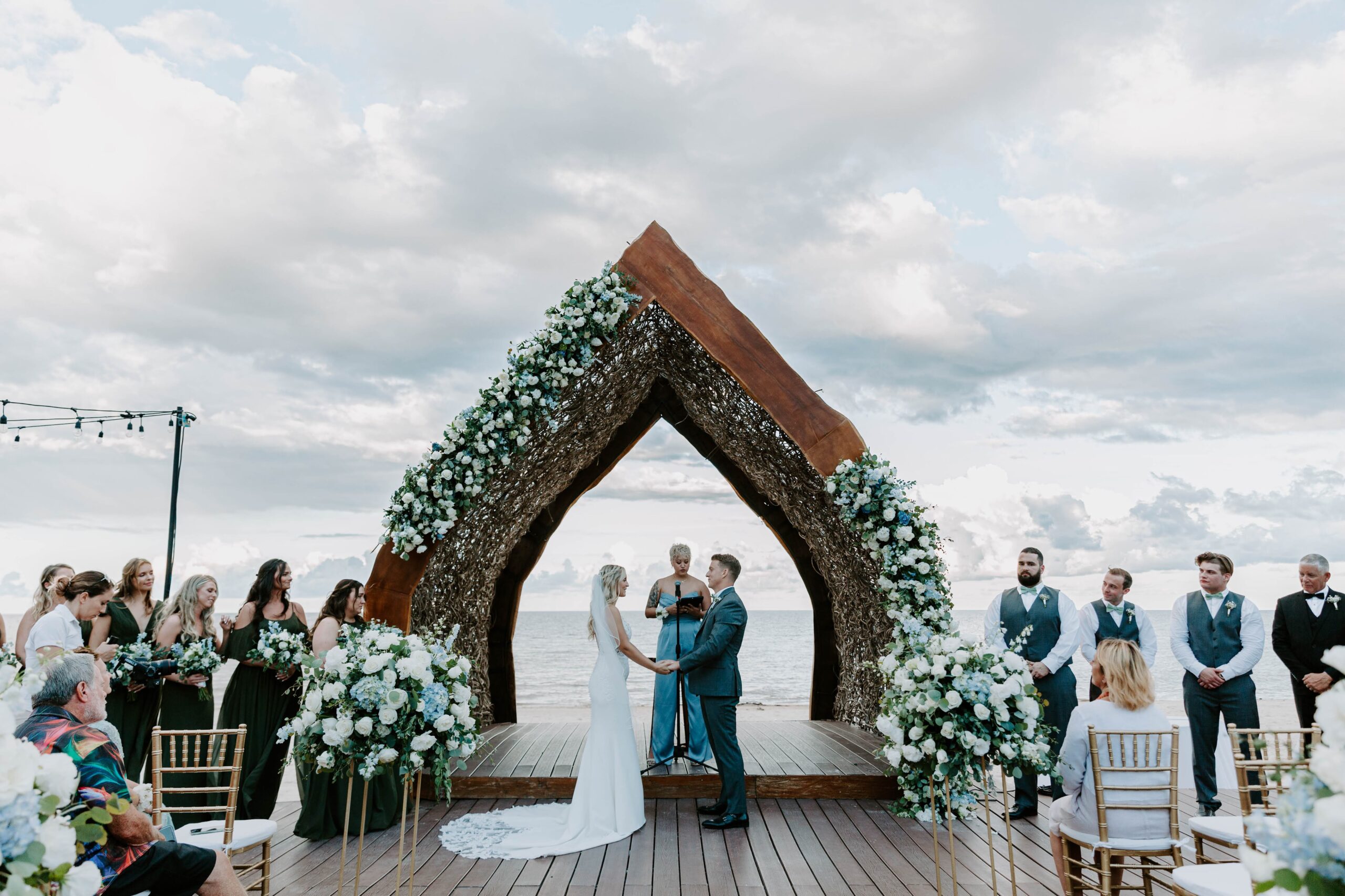 A couple standing together with their officiant at the waters edge during their Cancun wedding in Mexico