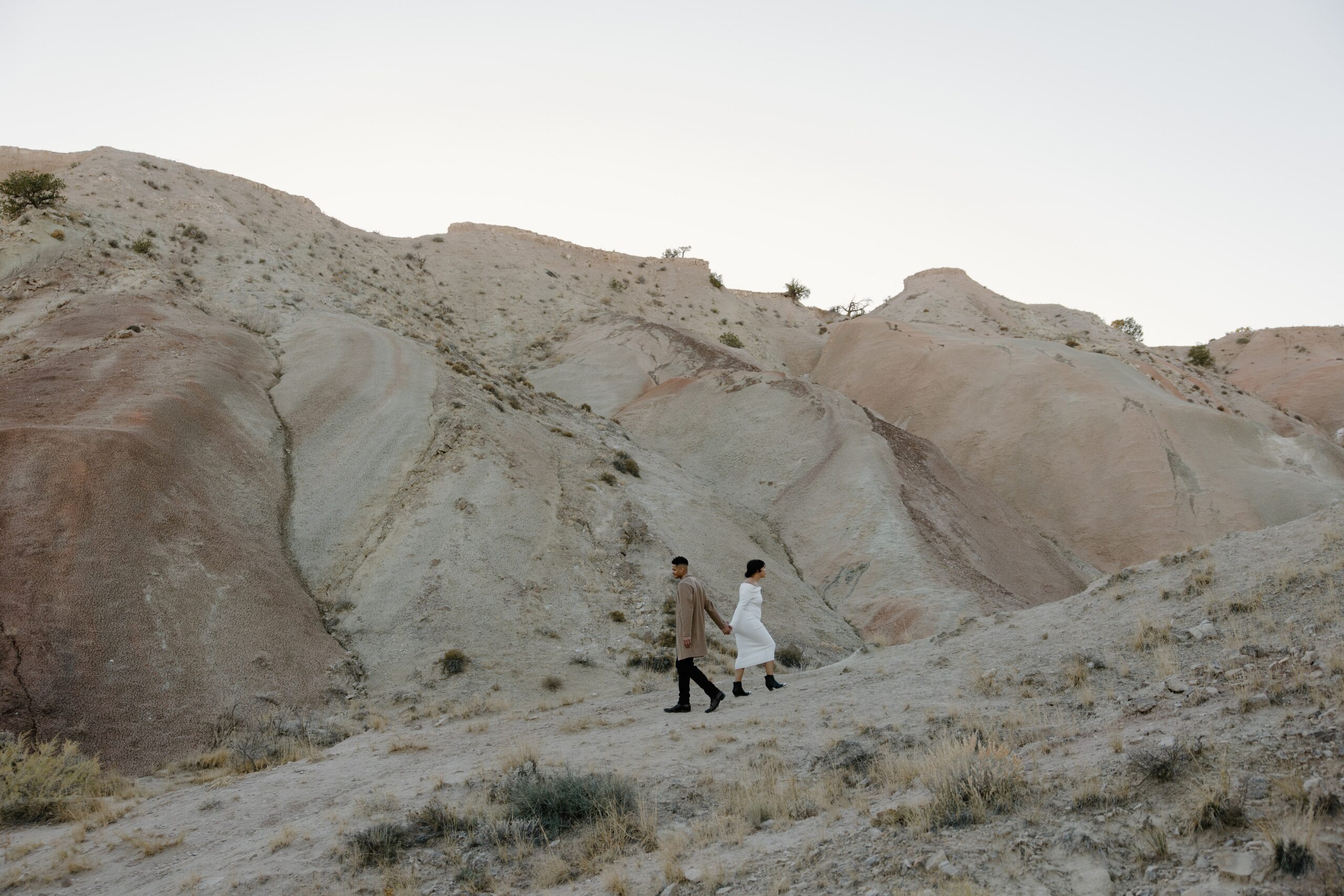 Couple walking through white desert hills during a fall maternity session