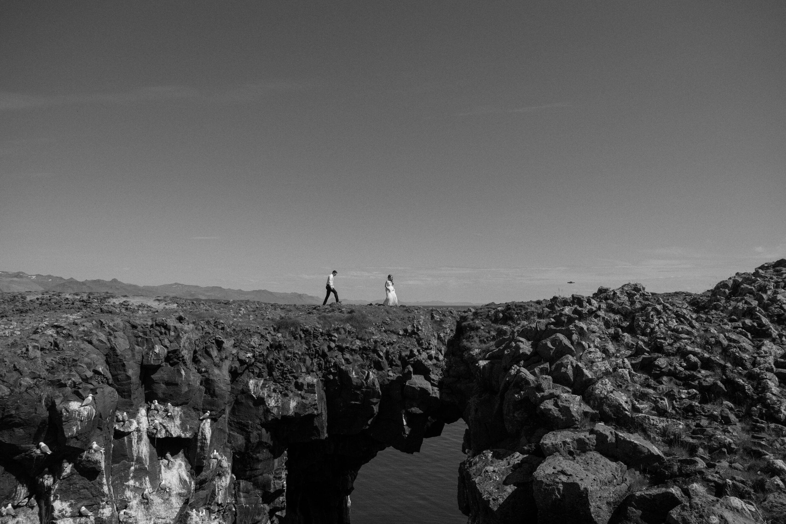 Scenic landscape view of West Iceland during summer as a couple walks over a natural bridge