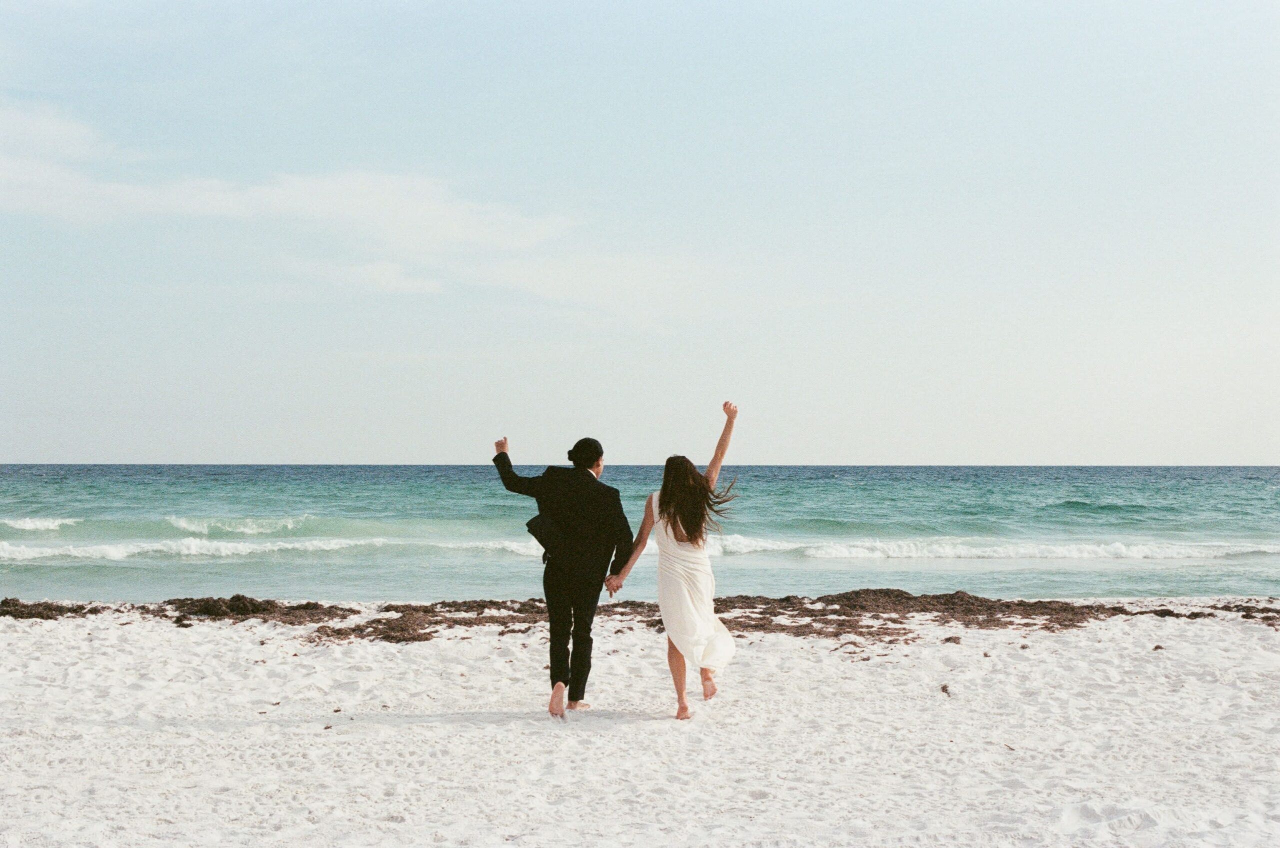 Couple running together in the Gulf of Mexico during a 30A beach elopement on film