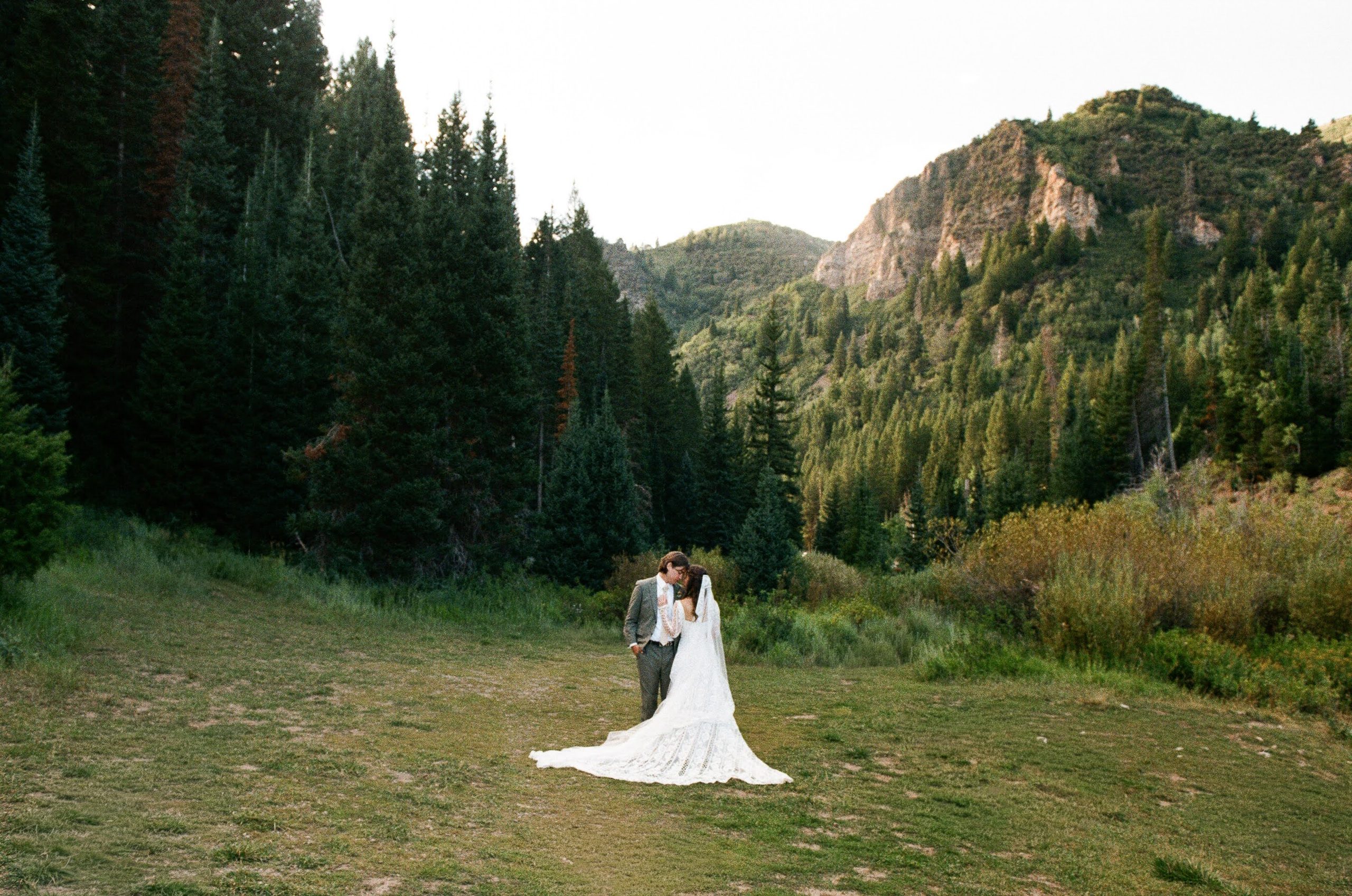 A couple embracing in a green meadow during their fall elopement in Utah on 35mm film